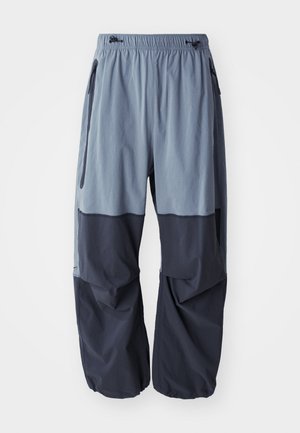 Locker sitzende, zweifarbige Outdoor-Hosen mit einem hellblauen oberen Bereich und einem dunkelblauen unteren Bereich, ausgestattet mit einem Kordelzugbund und Seitentaschen.