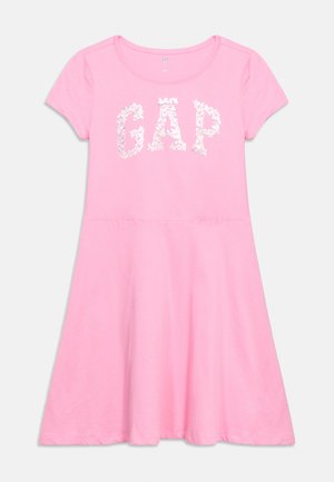 Rochie scurtă roz cu mâneci scurte, decolteu rotund și inscripția „GAP” formată din litere cu model floral pe piept.