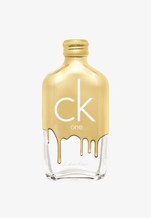 Kirkas lasipullo, jossa on kultainen korkki, ja siinä on valuvan kultaisen nesteen kuvio. Edessä on suuret valkoiset tekstit "ck" ja "one", ja etiketti on "Calvin Klein."