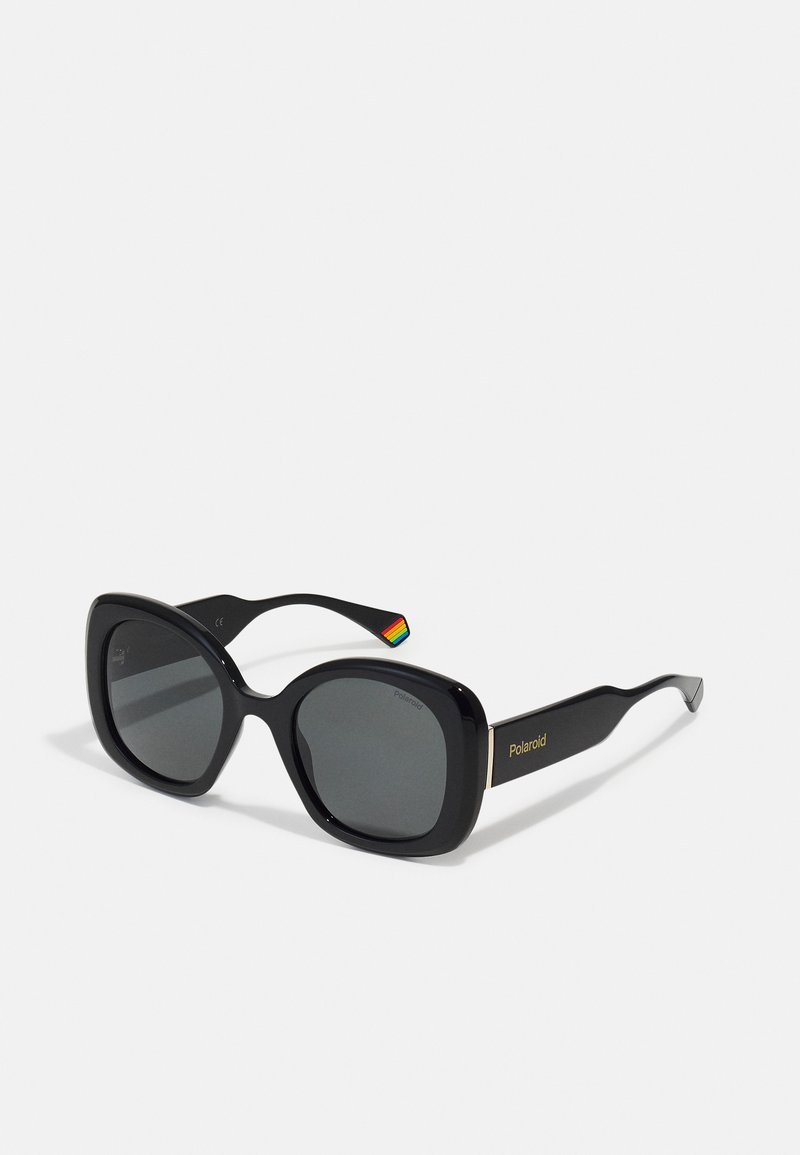 Black oversized sunglasses with a glossy finish, dark lenses, and a gold "Polaroid" logo on the frame. Features a multicolored stripe on the temple.