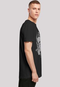 Svart bomull t-skjorte med grafisk trykk foran. Korte ermer, rund hals og løs passform. Matt tekstur, uformell design.