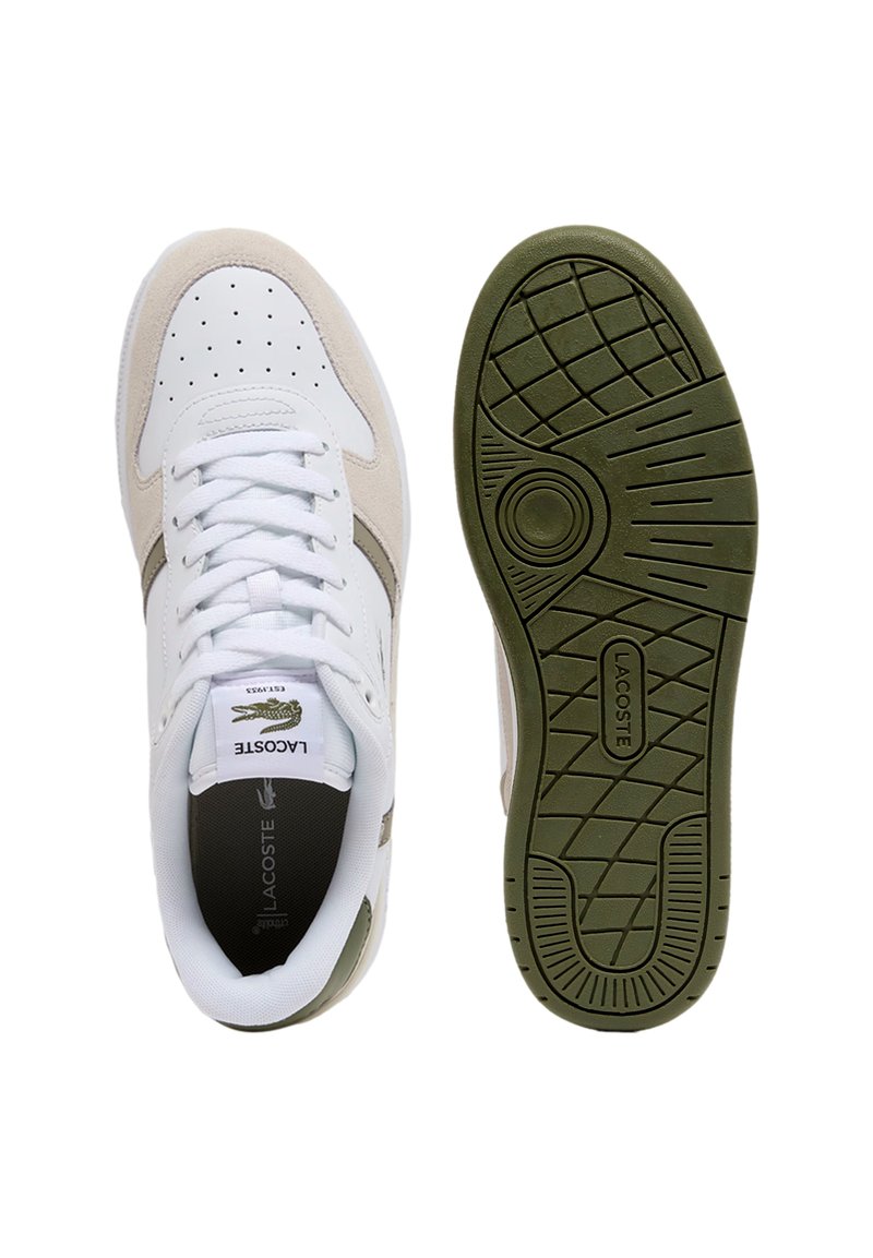 Lacoste-sneakers med øvre dele i hvidt læder og beige ruskindsstof, rund tå og en grøn gummisål med et struktureret mønster.
