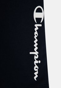Camiseta navy con un llamativo logo blanco de "Champion" en el lado izquierdo, hecha de material de algodón suave con una textura lisa.
