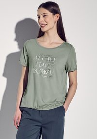 Jasnozielona koszulka z krótkim rękawem z okrągłym dekoltem i dekoracyjnym nadrukiem tekstu w kontrastowych kolorach z przodu.