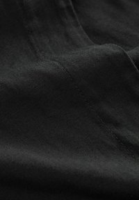 Tessuto nero con una superficie liscia, caratterizzato da delicate cuciture, che riflette una finitura opaca e un morbido caduta.