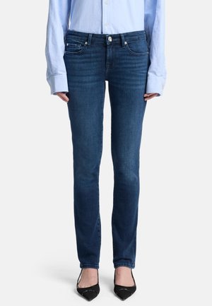 Donkerblauwe denim jeans met een getailleerd ontwerp, vijf-pocketstijl en een gladde textuur. Gecombineerd met zwarte pumps met een spitse neus.
