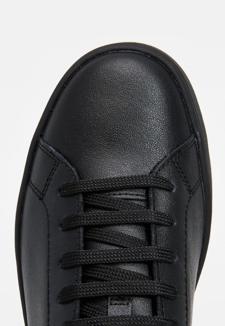 Czarne skórzane sneakersy z okrągłym noskiem, teksturowanym wykończeniem i przeszyciami. Posiadają czarne sznurówki i gładki język buta.