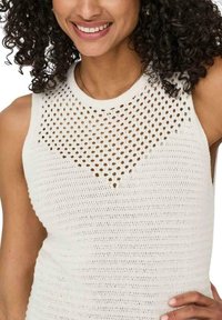 Top de punto sin mangas en color blanco roto, con un diseño texturizado y un patrón de malla abierta alrededor del escote y un ajuste estructurado.