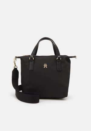Sac à main noir avec double poignée, bandoulière large amovible, et détails de logo et de quincaillerie dorés sur fond blanc.