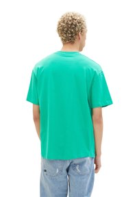 Green cotton t-shirt with a relaxed fit, short sleeves, and a straight hem. Features a simple, solid color design with no patterns.