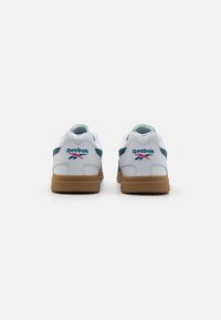 Baskets Reebok en cuir blanc avec accents bleu sarcelle, semelle en gomme naturelle et logo brodé sur le talon ; design épuré avec forme arrondie au niveau des orteils.