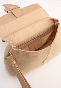 Sac à main en daim beige avec fermeture à bouton doré, intérieur doublé et bandoulière. Comprend une étiquette en cuir à l'intérieur avec l'inscription "KIOMI".