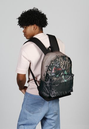Mochila con un diseño degradado que presenta arte grafiti de un ciclista. Hecha de tela, tiene correas negras y un bolsillo frontal.