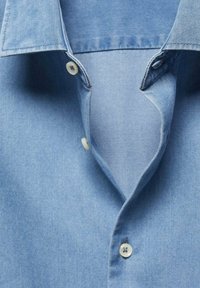 Jasnoniebieska koszula dżinsowa z klasycznym kołnierzykiem, zapięciem na guziki z białymi guzikami oraz miękkim, lekko teksturowanym materiałem.