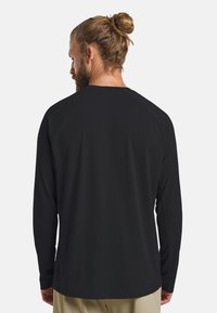 Langärmliges schwarzes Shirt aus leichtem, atmungsaktivem Material, mit Rundhalsausschnitt und Raglanärmeln für optimale Bewegungsfreiheit.