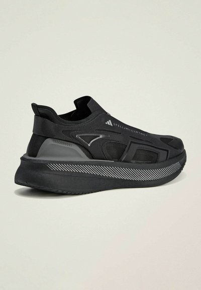 Scarpa da ginnastica nera con un design elegante, tomaia in mesh testurizzato, collo elastico e suola con motivo caratterizzato da strisce bianche.