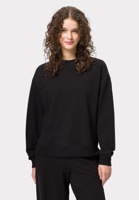 Černá mikina s kulatým výst�řihem, kleslými rameny a žebrovanými manžetami. Měkká textura látky; jednoduchý design bez vzorů nebo log. 