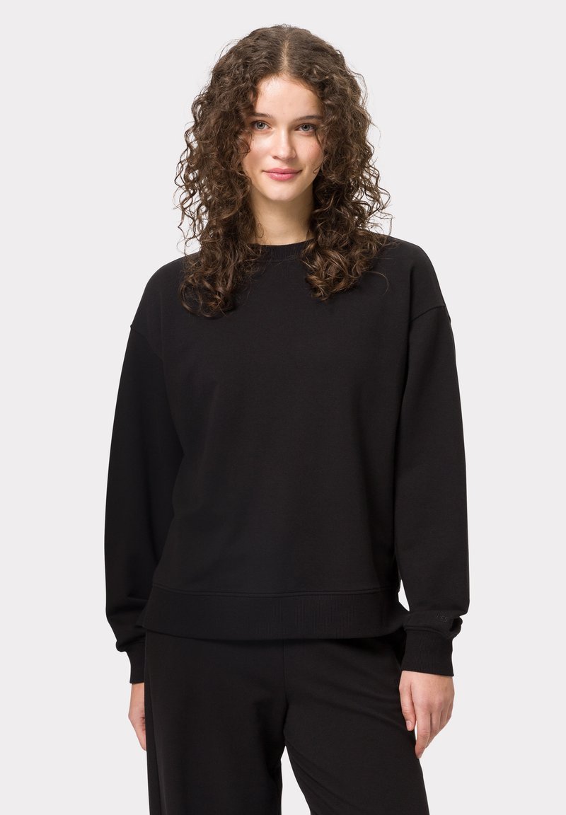 Černá mikina s kulatým výstřihem, kleslými rameny a žebrovanými manžetami. Měkká textura látky; jednoduchý design bez vzorů nebo log. 