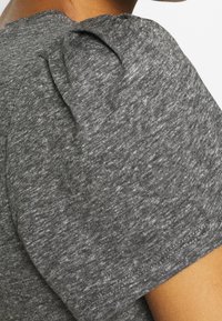 Grå tekstureret t-shirt med pufærmer, der har en rund halsudskæring og en glat overflade. Subtil farvevariation i stoffet.