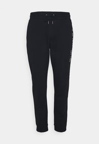 Schwarze Sweatpants aus weichem Stoff, mit einem Kordelzugbund, schmal zulaufendem Beinanschnitt und bedrucktem Logodetail an der Seite.