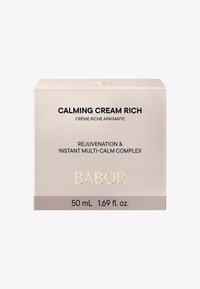 Kalmerende Crème Rijk in een zachte beige doos, met donkere tekst en gouden accenten. Inhoud: 50 mL, met een verjongende formule detail.