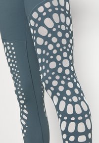Leggings athletic blu con un motivo testurizzato di punti bianchi di dimensioni diverse lungo il lato. Realizzati in tessuto elasticizzato che allontana l'umidità.