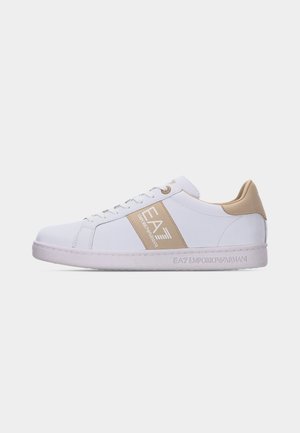 Biały sneaker niskiego profilu z beżowymi akcentami, logo EA7 Emporio Armani na boku i pięcie oraz białą gumową podeszwą.