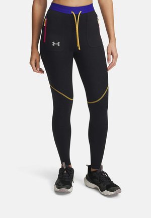 Leggings atléticos negros con cintura morada y cordón amarillo. Presentan dos bolsillos con cremallera y costuras en acento dorado.