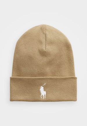 Beżowa wełniana czapka z zakładanym rękawem i białym haftowanym logo gracza polo z przodu. Wykonana z miękkiego, elastycznego materiału.