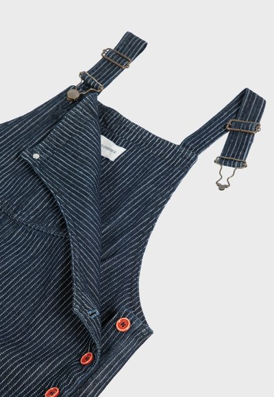 Denim overall with blue and white striped pattern, featuring metal clips, red buttons, and a folded collar tag visible on the inside.