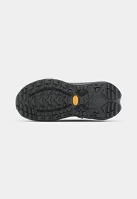 Svart gummiskoled med uttalade mönster, med en texturerad ytfinish och en Vibram-logotyp i mitten för förbättrat grepp.