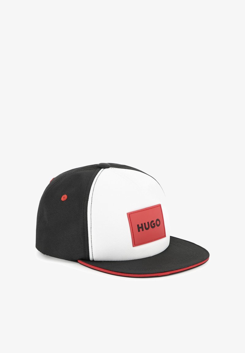 Casquette noir et blanc avec un patch rectangulaire rouge portant l'inscription "HUGO". Présente une visière plate, des coutures contrastées, et un accent rouge sur le bord de la visière.