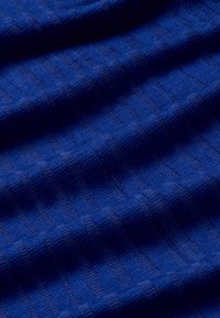 Tissu bleu texturé avec un motif côtelé fin. Le matériau semble doux et est tissé uniformément, créant une surface homogène.