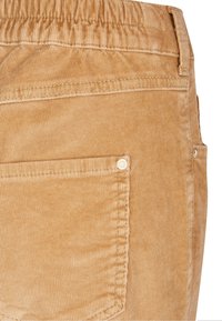 Beige kordfloddsbyxor med en samlad midja, sidoficka och vertikal ribbad textur. Anmärkningsvärda detaljer inkluderar en knappaccent.