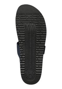 Semelle de sandale en caoutchouc noire avec une surface texturée comportant des motifs en relief, du texte en relief et un logo circulaire au talon.