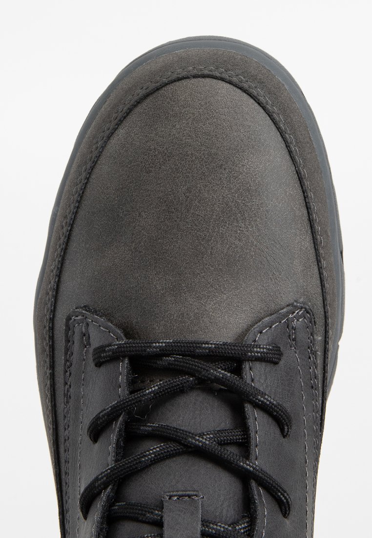 Chaussure en cuir noir avec une finition lisse, bout rond et couture grise contrastante. Équipée de lacets noirs et d'une semelle en caoutchouc texturée.