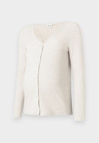 Ljus beige ribbad mammakardigan med V-hals, långa ärmar och knappstängning; mjuk textur och figursydd design runt magen.