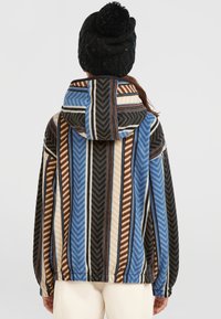 Chaqueta con capucha de forro polar que presenta un patrón de chevrón multicolor en azul, marrón, negro y crema. Textura suave con puños y dobladillo elásticos.