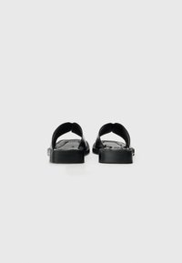 Svarta flip-flops med rund tå, öppen häl och texturerad sula. Tillverkade av gummi, med en enkel, böjd remdesign.
