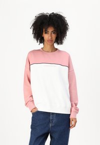 Hvit og rosa genser med lange ermer, med en horisontal svart linje, og en "Guess Jeans" logo på brystet. Bomullsmateriale.