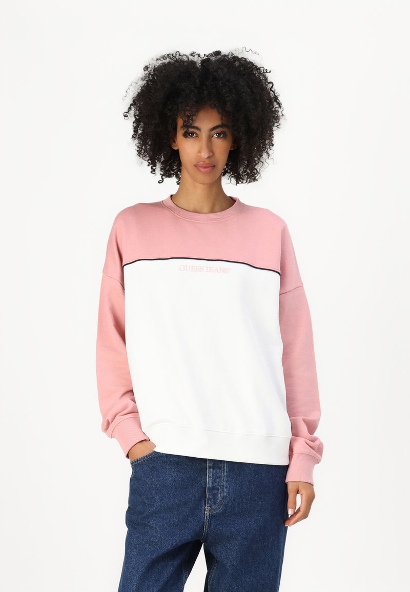Hvit og rosa genser med lange ermer, med en horisontal svart linje, og en "Guess Jeans" logo på brystet. Bomullsmateriale.