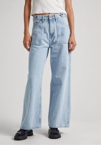 Ljusblå vida jeans tillverkade av denim med två framfickor, knapplås och dragkedja, samt subtil blekning längs benen.