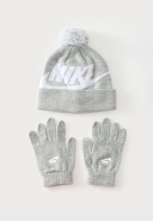 Bonnet gris en tricot avec un pompon et des gants assortis, tous deux avec un logo Nike blanc.