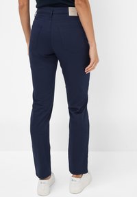 Marineblauwe broeken met een slim fit, voorzien van twee achterzakken, gestikte details en een leren merkpatch op de tailleband.