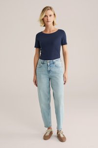 Marineblaues eng anliegendes T-Shirt kombiniert mit hellblauen High-Waist-Jeans. Die Schuhe sind braun, geschnürt und aus strukturiertem Material. Einfaches und sauberes Design.