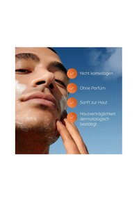 Facial skincare product shown on a smooth-skinned male applying cream. Background features clear blue sky; text highlights key benefits.