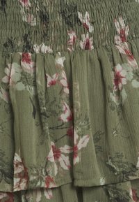 Tejido ligero con estampado floral que presenta tonos de verde y rosa. Cuerpo fruncido con detalles de falda de volantes en capas.