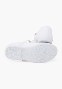 Scarpe da ginnastica bianche con punta rotonda, dotate di una suola in gomma bianca. La suola presenta un design a motivo con fiori e cuori.