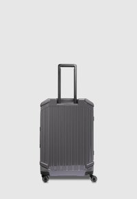 Valigia rigida di colore grigio scuro, con scanalature verticali, quattro ruote e manico telescopico per una facile manovrabilità.