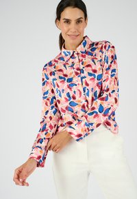 Camicia button-up rosa con un motivo di foglie astratte colorate nei toni del blu, rosso e viola, con maniche lunghe e colletto classico.